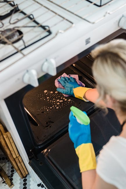 A modern kitchen scene emphasizing surface cleaning and hygiene, featuring a black range hood above a stovetop with a steaming pot, indicating recent cooking activity. The stainless steel range hood i